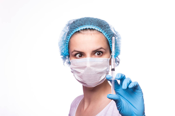 beautiful young girl in medical mask wearing glasses and gloves is holding a syringe - Photo, Image