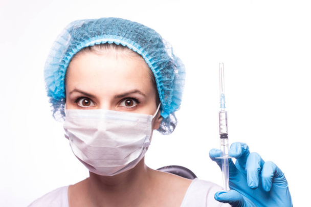 beautiful young girl in medical mask wearing glasses and gloves is holding a syringe - Foto, immagini