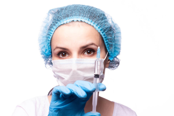 beautiful young girl in medical mask wearing glasses and gloves is holding a syringe - Valokuva, kuva