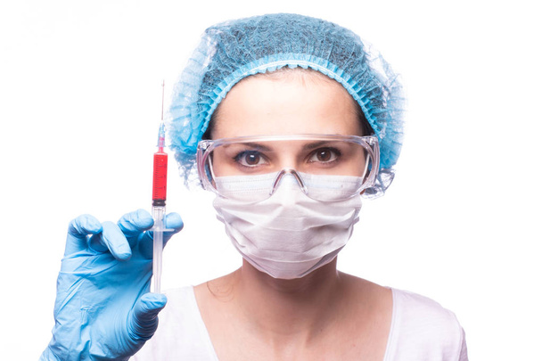 beautiful young girl in medical mask wearing glasses and gloves is holding a syringe - Photo, image