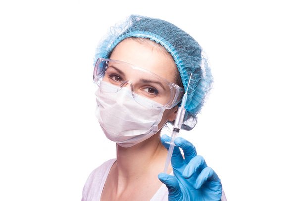 beautiful young girl in medical mask wearing glasses and gloves is holding a syringe - Photo, image