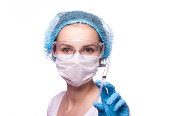 beautiful young girl in medical mask wearing glasses and gloves is holding a syringe - Foto, Imagen