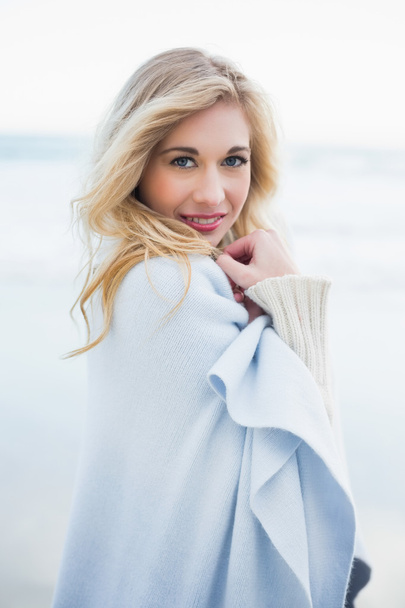 Cute blonde woman covering herself in a blanket - Foto, imagen