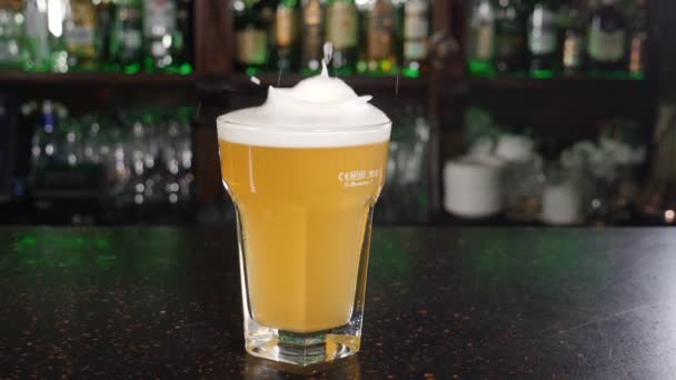 Buz küpleri bira dolu bardağa düşüyor. Ağır çekim. Bar tezgahında köpük ve su sıçraması. Beslenme ve içecek konsepti. Bardaktan dökülen biralar bitlenir. hd - Video, Çekim