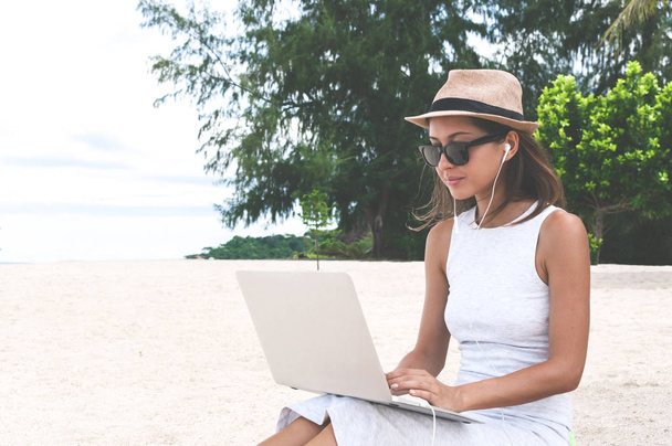 Young woman working with laptop computer on tropical island beach under palm trees Freelance  concept - 写真・画像