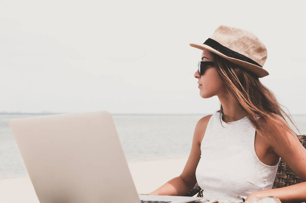 Young woman using laptop computer on a beach. Freelance  concept - Photo, image
