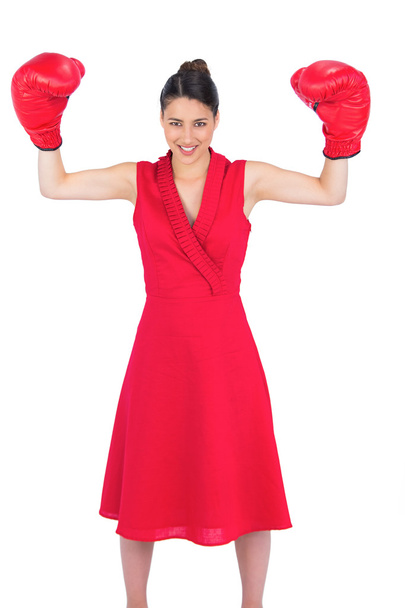 Smiling gorgeous brunette in red dress wearing boxing gloves - Photo, image