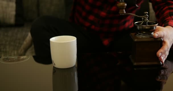 Man zet koffiebonen in een antieke koffiemolen met rode en zwarte vierkante hipster stijl shirt - Video