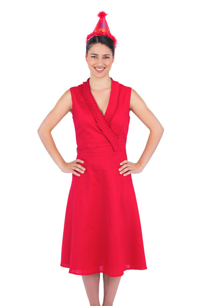 Smiling gorgeous brunette in red dress wearing party hat - Φωτογραφία, εικόνα