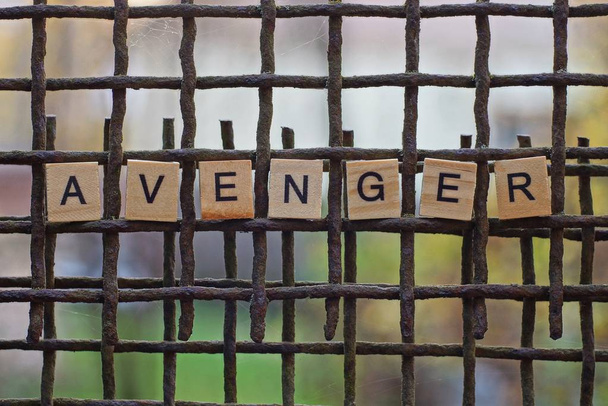 mot vengeur de lettres en bois sur une grille en métal brun rouillé
 - Photo, image