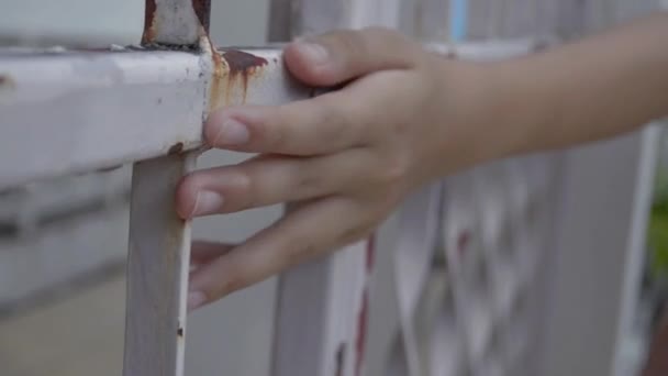 close-up hand van een eenzaam meisje is het aanraken van de roestige metalen hek in de voorkant van het huis. - Video