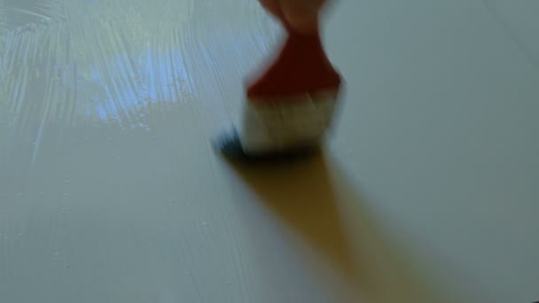 A kilátás a vállára egy munkavállaló alkalmazó ragasztó ecsettel egy fehér forgácslap gyártási festék ragasztó felett. - Felvétel, videó