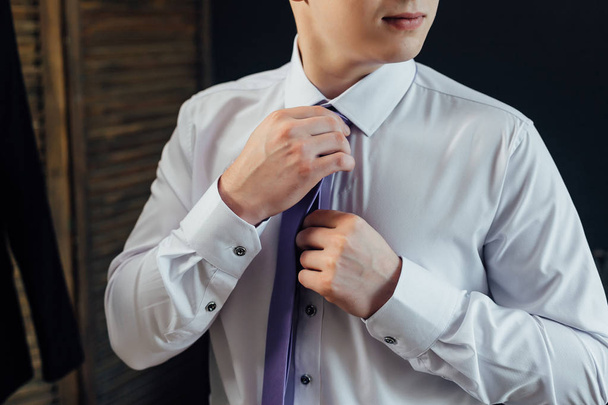 Мужчина в рубашке выпрямляет галстук
 - Фото, изображение