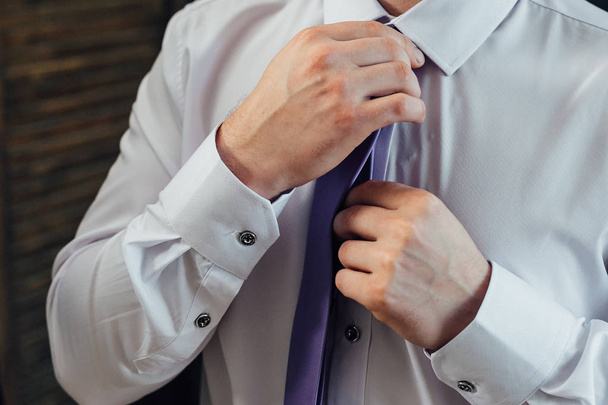 Mies paidassa suoristaa solmionsa.
 - Valokuva, kuva