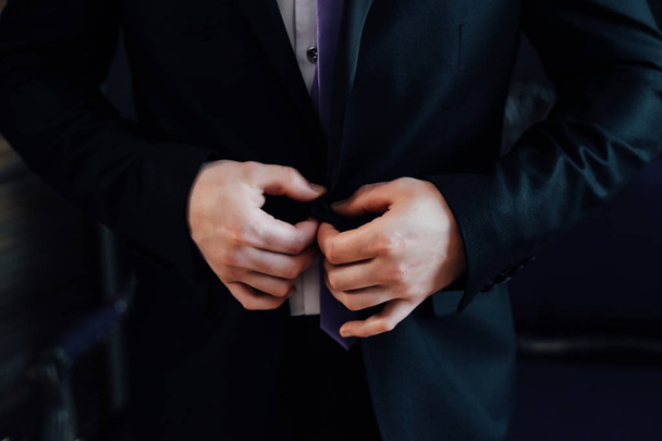 die Hände einer Jacke zuknöpfen. Stilvoller Mann im Anzug - Foto, Bild