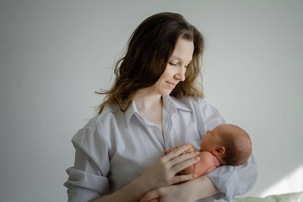 Hübsche Frau hält ein neugeborenes Baby im Arm - Foto, Bild