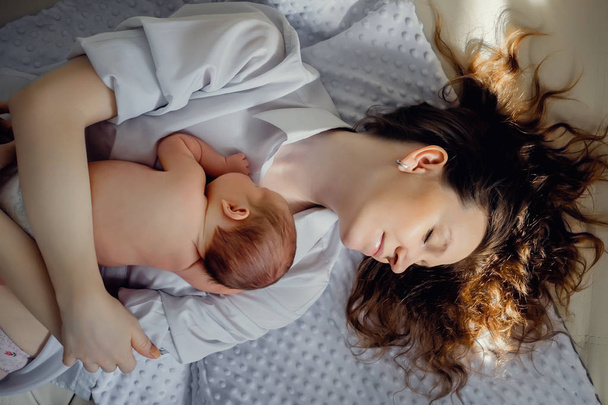 A newborn baby boy is lying on mom's chest. In a bright room. In the sun - Foto, afbeelding