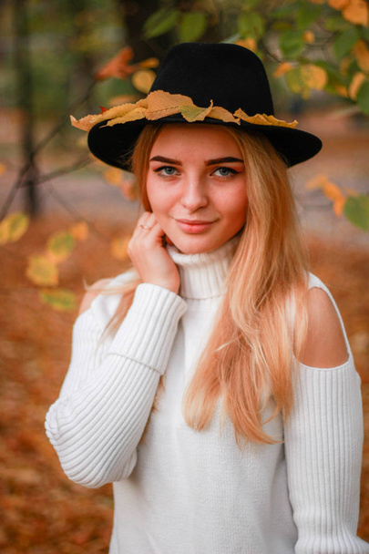 Autumn girl portraits. Model in white sweater .Black hat with ye - Photo, Image