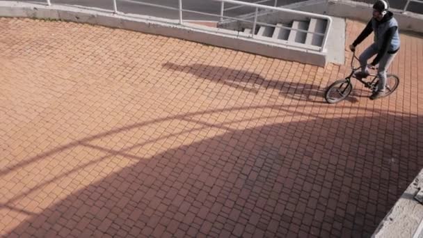 Young male ride on bmx bicycle in the city - Materiał filmowy, wideo