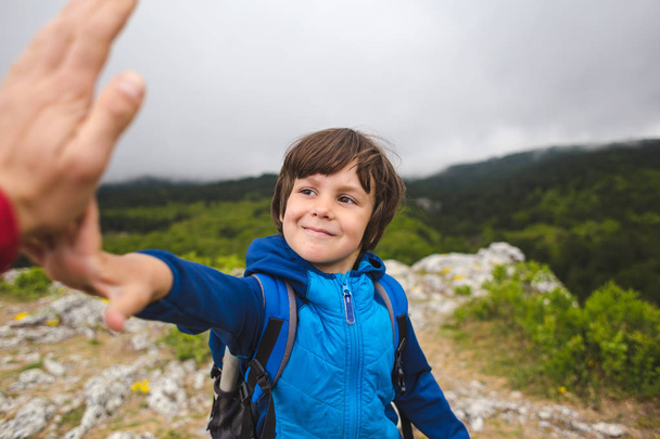Sırt çantası olan bir çocuk dağın tepesine tırmandı ve beş veriyor.. - Fotoğraf, Görsel