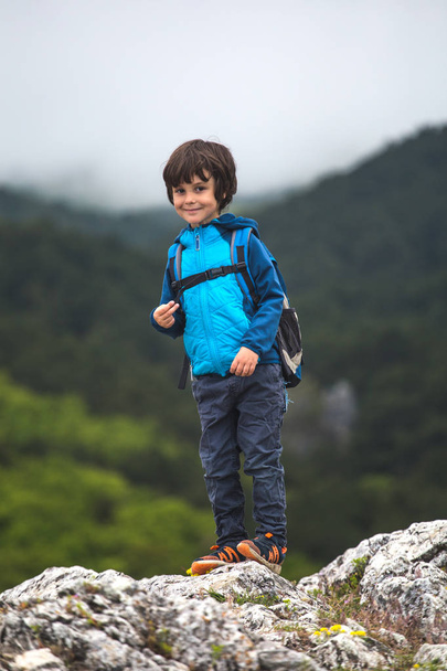 Chlapec s batohu stojí na vrcholku hory. - Fotografie, Obrázek