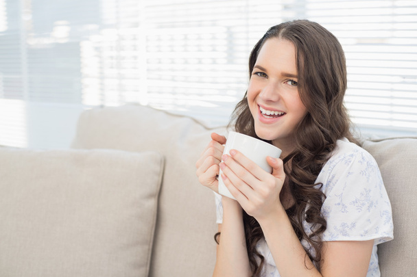 Cheerful young woman in pyjamas having coffee - Fotografie, Obrázek