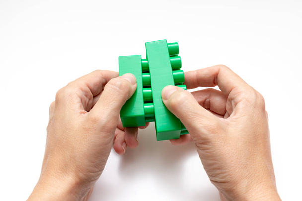 Hands constructing from colorful toy plastic bricks, blocks for building on white background - Фото, изображение