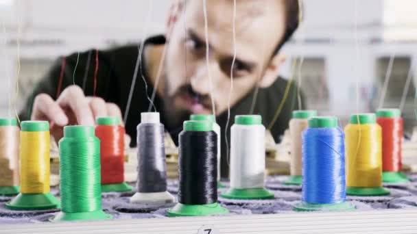 Muž v továrně na tkaniny kontroluje šicí nitě - Záběry, video