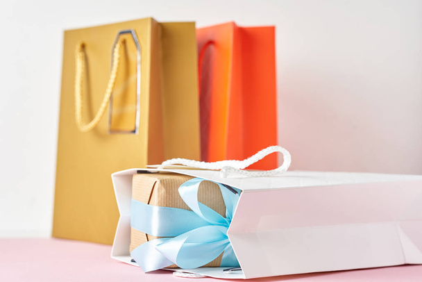 Colorful paper shopping bag and gift box with blue ribbon on a w - Zdjęcie, obraz