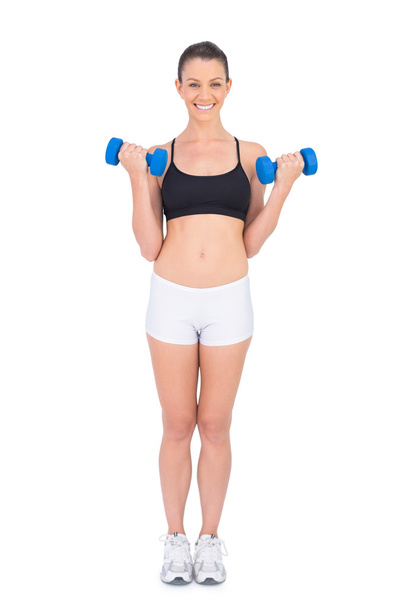 Smiling fit woman working out with dumbbells - Fotoğraf, Görsel