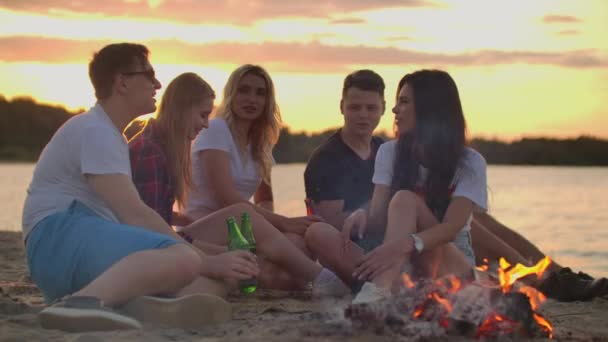 Mladí lidé si užívají teplý letní večer na písečné pláži - Záběry, video