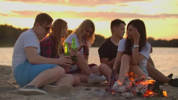 Młodzi ludzie cieszą się ciepłym letnim wieczorem na plaży - Materiał filmowy, wideo