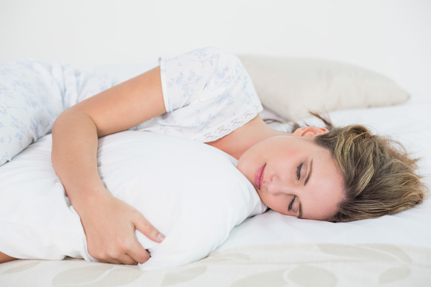 Peaceful woman lying on bed embracing pillow - Φωτογραφία, εικόνα