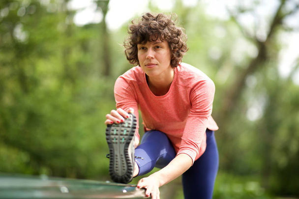 Retrato de mujer deportiva estirando los músculos al aire libre
 - Foto, Imagen