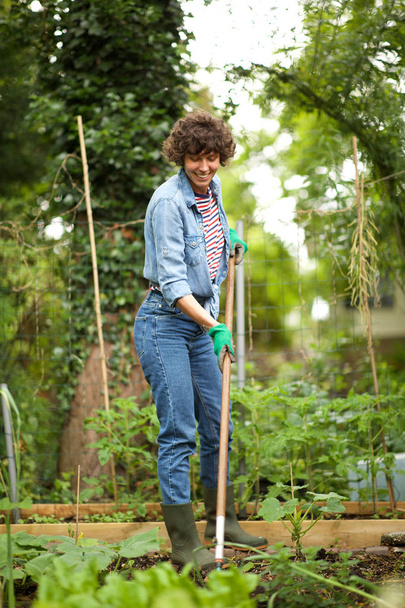 Full body portrait of happy  woman raking garden - Valokuva, kuva