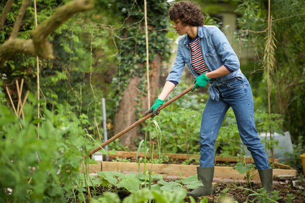 Full body portrait of woman raking garden - Foto, imagen