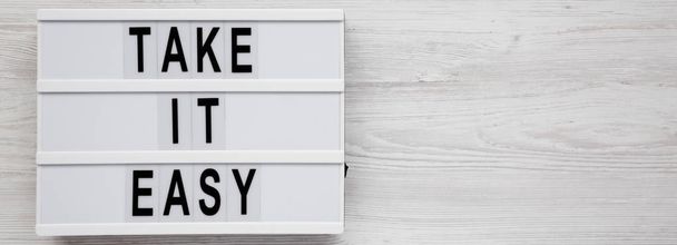 "Πάρτε εύκολο" λέξεις σε ένα lightbox σε ένα λευκό ξύλινο φόντο, - Φωτογραφία, εικόνα