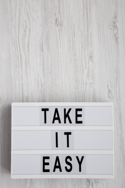 "Πάρτε εύκολο" λέξεις σε ένα σύγχρονο πίνακα σε μια λευκή ξύλινη επιφάνεια - Φωτογραφία, εικόνα