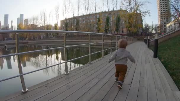 Child boy runs on a wooden platform - Imágenes, Vídeo