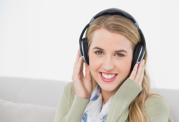 Cheerful cute blonde listening to music sitting on cosy sofa - Foto, Imagem