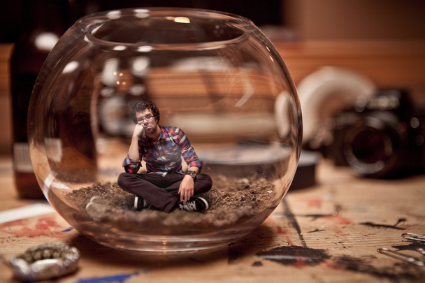 Unhappy Miniature man trapped inside a fishbowl. - Photo, Image