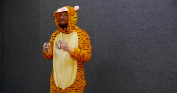 Funny business worker in open space wearing kigurumi, tiger pajama clothing and playing jingle bells, percussion music instrument, having fun at work during break time. - Video, Çekim