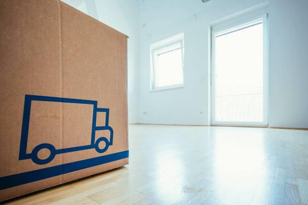 Move. Cardboard box in a clean and bright room with wooden floor. Moving into a new home.  - Photo, Image