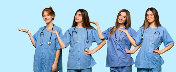 Gruppe von Krankenschwestern mit Kopierraum imaginär auf der Handfläche, um eine Anzeige einzufügen - Foto, Bild
