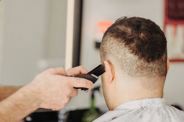Fryzjer podejmowania stylowe fryzury z profesjonalną maszyną w salonie fryzjerskim. Fryzura dla Tureckiego mężczyzny - Zdjęcie, obraz