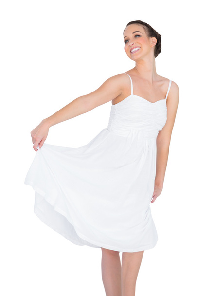 Smiling beautiful young model in white dress dancing - Фото, изображение