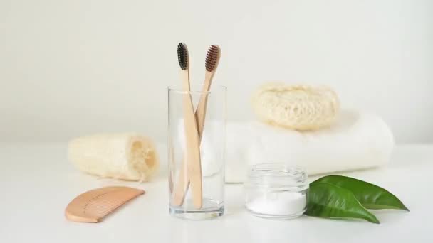 Wooden bamboo toothbrush falls into glass to other brushes and bathroom zero waste products on white background - Footage, Video