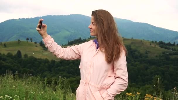 Nő csinál szelfi fotók okostelefon kilátással a hegyekre - Felvétel, videó