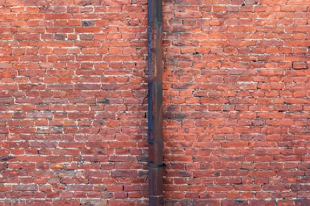Old red brick wall background. Rusty metal downpipe in the center. - Photo, Image