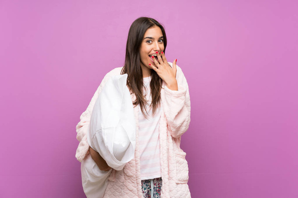 Young woman in pajamas and dressing gown over isolated purple background with surprise facial expression - Photo, Image